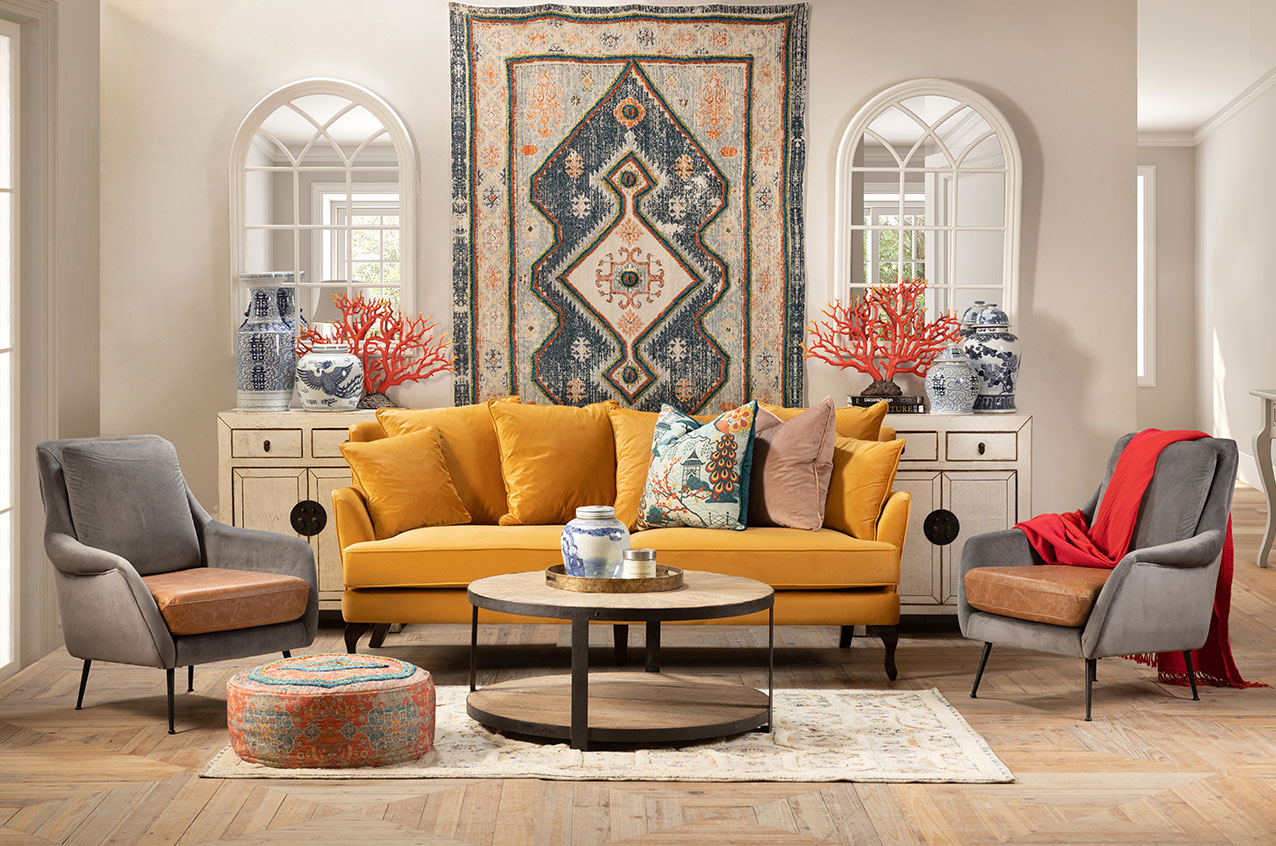Blue velvet sofa with handwoven rugs and round metal coffee table