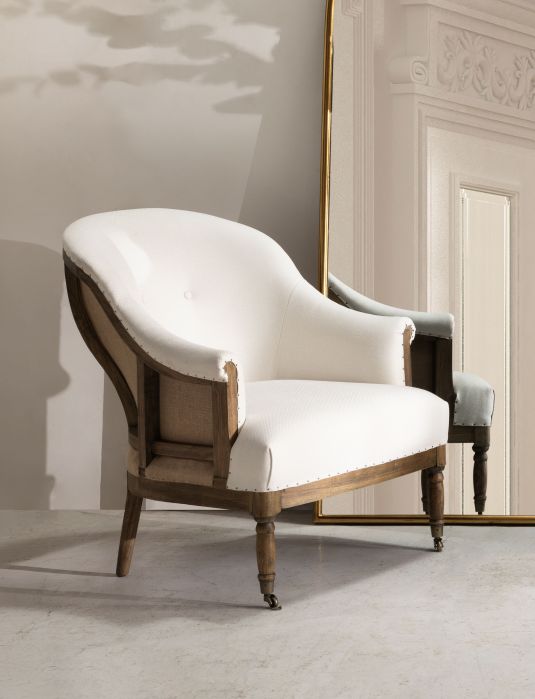 Deconstructed occasional chair with castors, upholstered in ivory fabric.